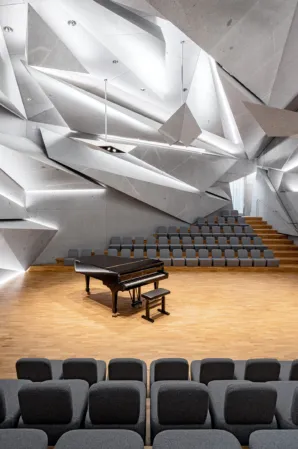 concert hall with mirrored rows of seats and a piano in the center