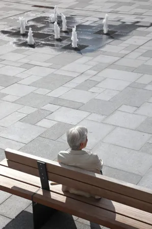 woman sitting on a wooden bench overlooking a fountain field