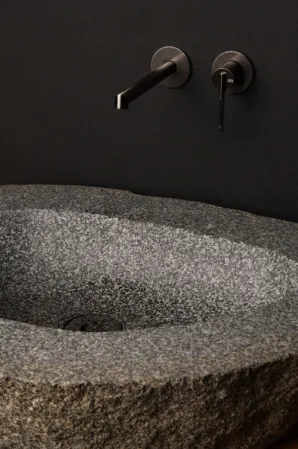 Basin made out of boulder infront of a black wall