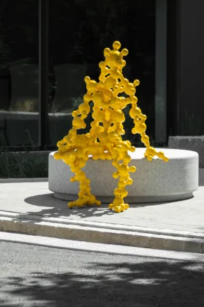 A yellow art figure sits on a granite polar