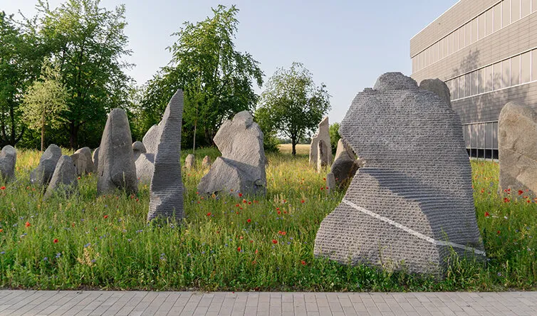 artwork made of boulders arranged in a park with flower meadow