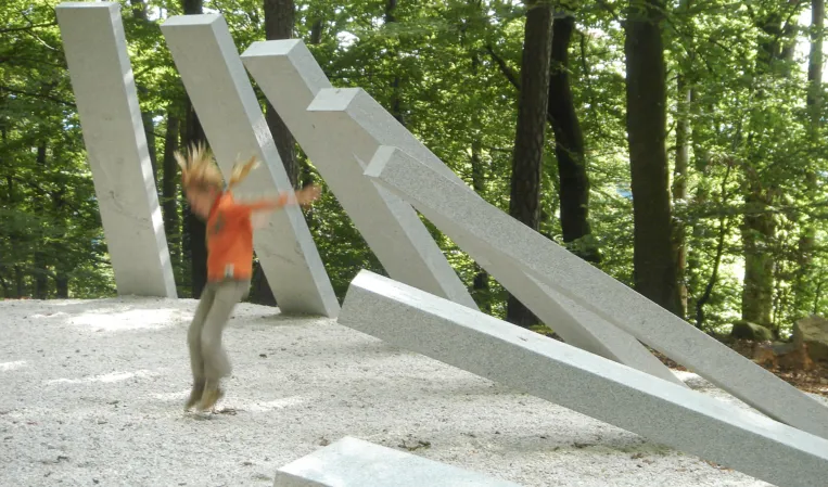 child playing in a park with an artwork made of prestressed granite posts