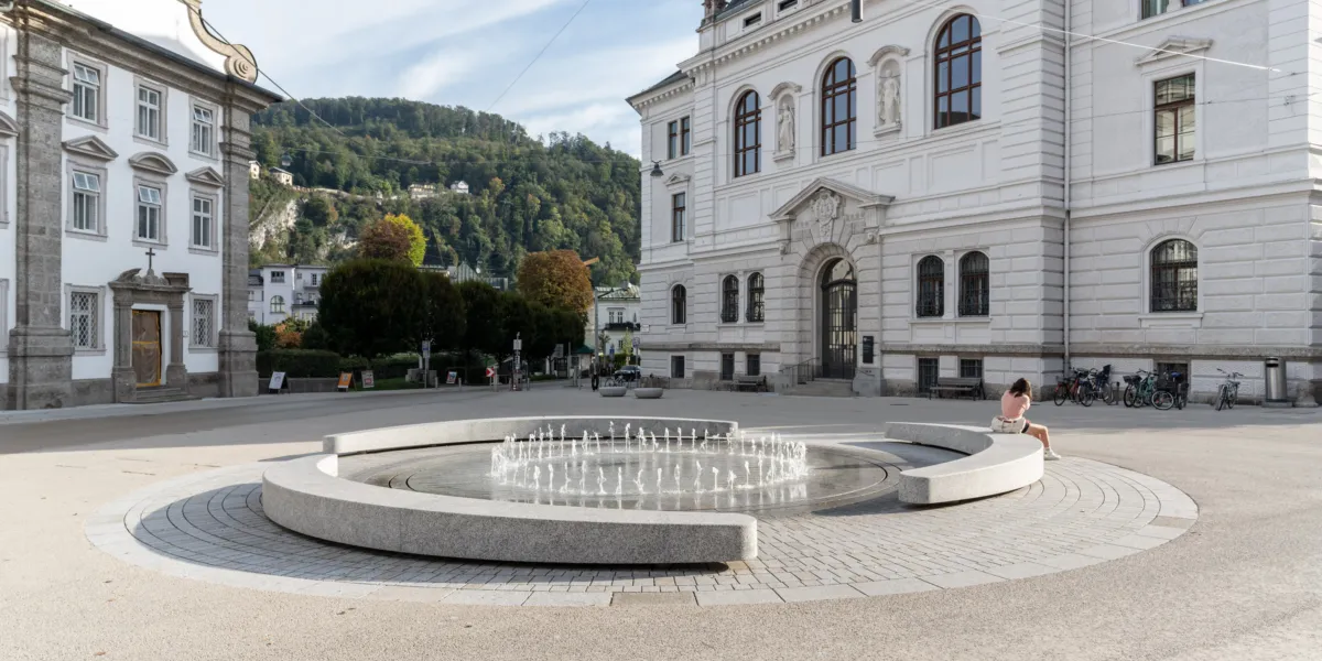 Rund angeordneter Brunnen mit einem Fotänenfeld in der Mitte
