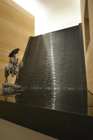 Wasserwand aus schwarzen Granit mit einer Skulptur davor