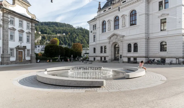 Rund angeordneter Brunnen mit einem Fotänenfeld in der Mitte