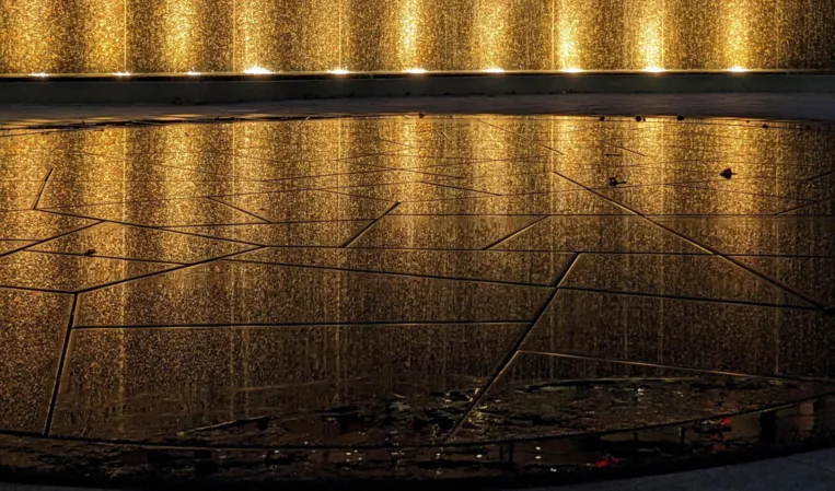 Fontänenfeld bei Nacht mit reflektierenden Lichtspiegelung