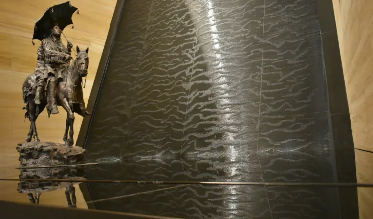 Wasserwand aus schwarzen Granit mit einer Skulptur davor