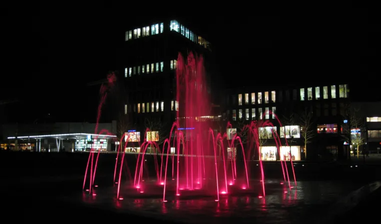 Große Wasserfontänen bei Nacht rot beleuchtet
