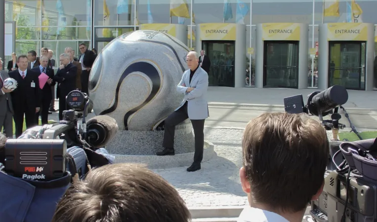 Franz Beckenbauer posiert vor der schwimmenden Kugel aus Granit
