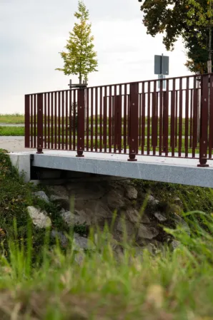 weinrotes Geländer oberflächig montiert auf einer Granitbrücke