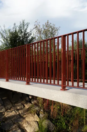 Seitliche Ansicht einer Granitbrücke mit roten Geländer