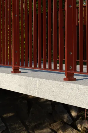Seitliche Ansicht einer Granitbrücke mit roten Geländer