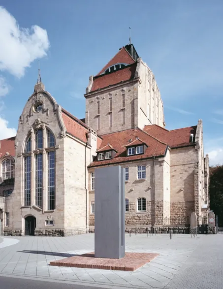 Granite artwork resembling a tuning fork, situated on a church forecourt